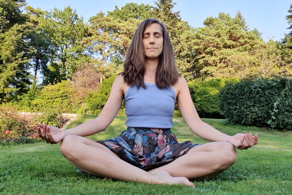 Catherina, Autorin des Blogs Wegweiser Neurodermitis, meditiert bei Sonnenschein in der Natur.
